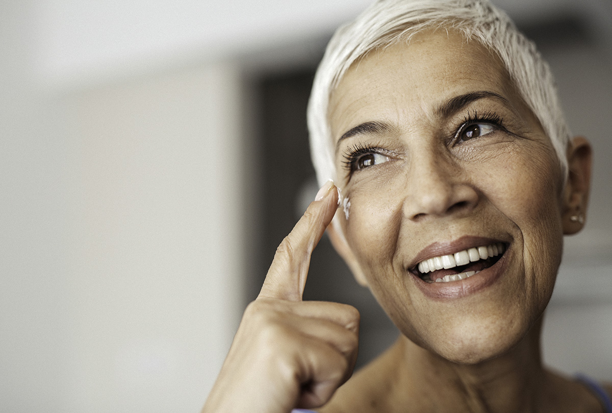 Frau schmiert sich eine Creme ins Gesicht